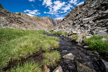 Lush green grass, a flowing creek and large rocks along the mountain hiking trail in the 20 Lakes Basin - Eastern Sierra Nevada California