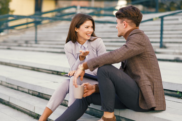 Young business people communicating on a coffee break outdoors .They are sitting on a staircase