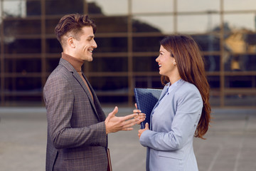 Happy business couple standing together outdoors and communicating.
