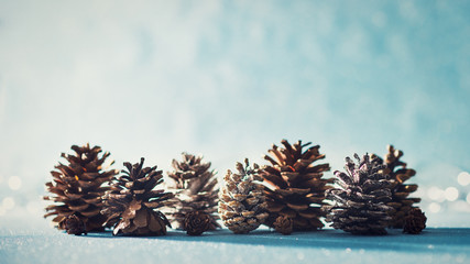 Beautiful Christmas Background. Pine cones on shiny blue background with defocused christmas lights in the background.