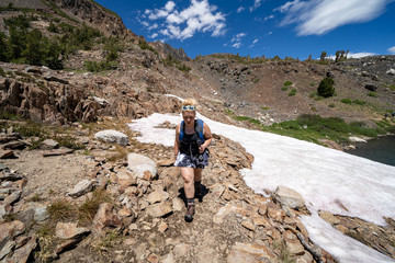 Naklejka premium Female hiker looking distressed after hiking through a small snow field in the Eastern Sierra California, 20 Lakes Basin hike