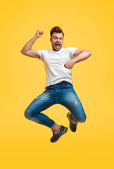 Fototapeta na wymiar Playful jumping man on yellow background