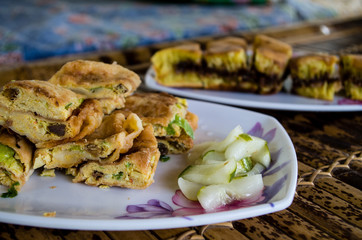 MARTABAK TELUR - stuffed pancake or pan-fried bread Indo-style on a plate, close-up with TERANG BULAN in background.