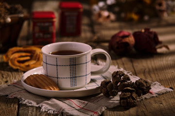 English Tea Time. Cup of tea with cookies on wooden table, rustic homemade interior.