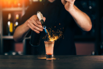 The bartender makes a cocktail of fire. Hiroshima cocktail. The barman ignites the lighter on the bar