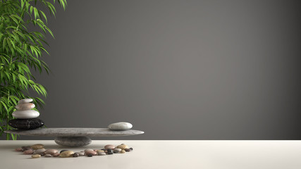 Empty interior design feng shui concept zen idea, white table or shelf with pebble balance and green bamboo, over dark gray background copy space