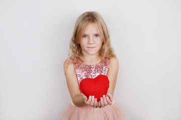 7322839  beautiful blond girl with red heart on a white background. Child with a heart for Valentine's day