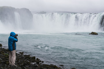 Photographer taking picture of Godafoss waterfall, Iceland