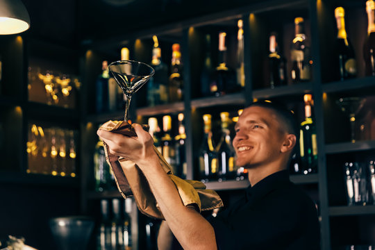 Barman watches a crystal glass. The bartender cleaning the glass on the bar