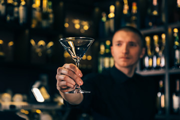 Barman watches a crystal glass. The bartender cleaning the glass on the bar