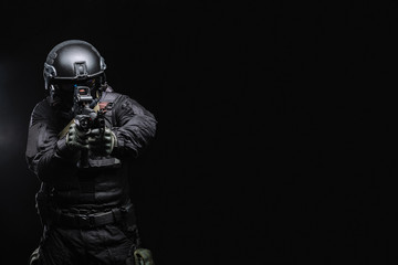 Airsoft player in an outfit with weapons on a black background - obrazy, fototapety, plakaty