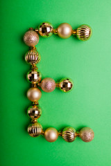 Letter E made of Christmas toys on green background. ABC