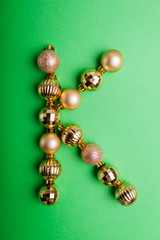 Letter K made of Christmas toys on green background. ABC