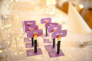 Purple name cards for guests and empty wine glasses on the table decorated for wedding
