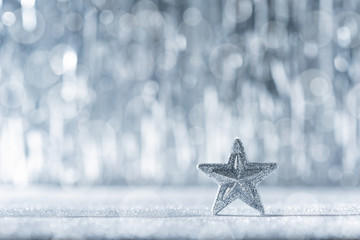 Shiny silver christmas star with defocused christmas lights in the background.