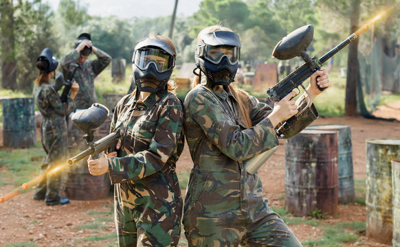 Portrait of confident female paintball players with marker guns