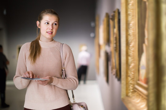 Glad girl holding guide book in museum