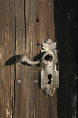 Beautiful vintage metallic latch on a wooden door with spider web.