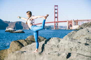 Woman making yoga poses in Baker beach, San francisco