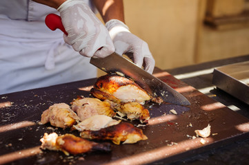 The chef's hand cuts the grilled chicken