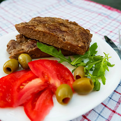 Pleskavitsa. Dish of Balkan cuisine from minced meat with vegetables on white plate.