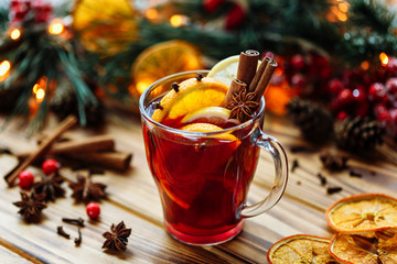 Christmas mulled red wine with spices and fruits on a wooden rustic table. Traditional hot drink at...