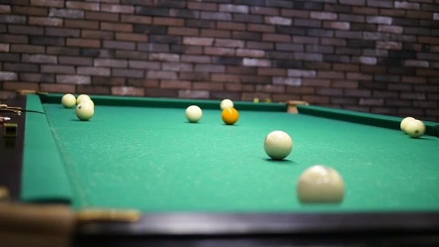Playing billiards Blowing a cue on the ball, the ball hit the pocket, the ball did not hit the pocket, billard, green table, breaking balls, muffled light, billiard club