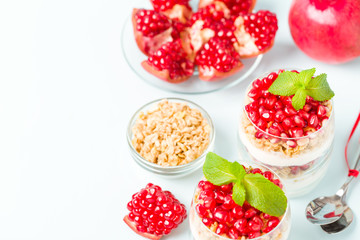 Pomegranate parfait - sweet organic layered dessert with granola flakes, yogurt and ripe fruit seeds.