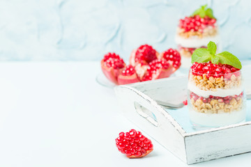 Pomegranate parfait - sweet organic layered dessert with granola flakes, yogurt and ripe fruit seeds.