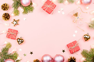 Fototapeta na wymiar Christmas background with fir branches, lights, red giftboxes, pink decorations on pink