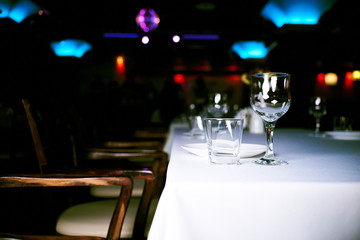 a chair stands near the table on which there is an empty glass and a plate