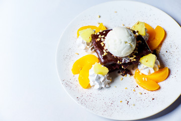 delicious dessert, cake dessert with brown crust, ice cream and dried apricots, lies on a white plate