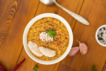 Turkish lentil bulgur soup sprinkled with pepper in a white bowl on a wooden background