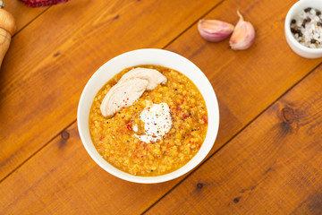 Turkish lentil bulgur soup sprinkled with pepper in a white bowl on a wooden background