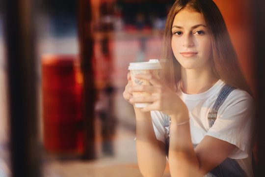 young attractive pretty girl at cafe with coffee relax at morning throuth glass
