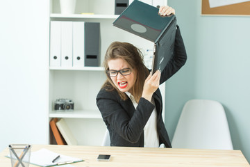 Stress, office and people concept - stressed angry business woman breaking up her computer
