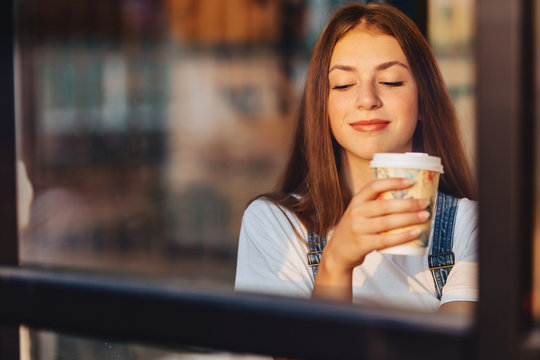 young attractive pretty girl at cafe with coffee relax at morning throuth glass
