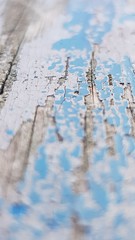 Selective focus shot of weathered blue paint wearing from rotten wood.