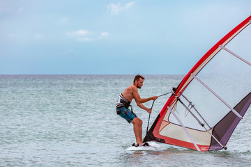Surfer riding waves in a beautiful sunny day. Young man enjoying the wind and the ocean surfing.