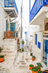 Traditional houses with blue doors and windows in the narrow streets of greek village in Mykonos in Greece