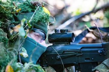 special forces, soldier assault rifle with silencer, optical sight. behind cover waiting in ambush