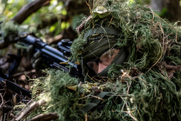 special forces, soldier assault rifle with silencer, optical sight. behind cover waiting in ambush