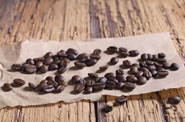 Coffee beans scattered on a paper on an old wood