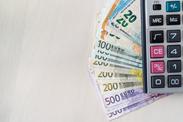 Euro banknotes with calculator on wooden desk
