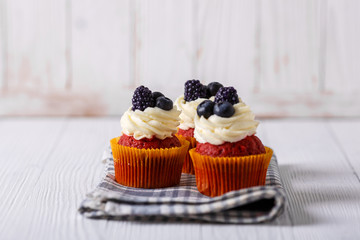 Tasty red velvet cupcakes on wooden table.