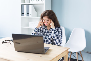 Fototapeta premium Young woman has a headache while working on laptop in office