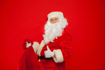 Christmas. Portrait of Santa Claus with huge red sack thumb looking at came