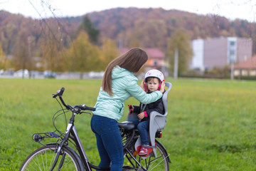 Use a bicycle helmet. A woman puts a bicycle helmet on a child.