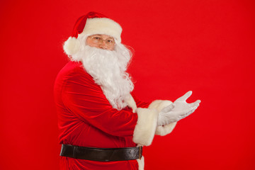 Fototapeta na wymiar Santa Claus pointing in blank a place, red background