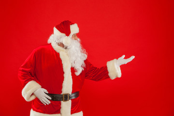 Christmas. Santa Claus pointing in blank a place, red background